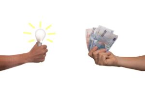 two-men-hand-holding-bunch-of-cash-and-a-bulb-with-hand